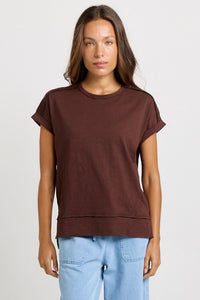 Betty Basics Shirley Short Sleeve Tee in Chocolate — full-length front view of relaxed cotton slub tee in chocolate brown with crew neckline, rolled cuffs and high-low hem, styled with light blue wide-leg jeans.