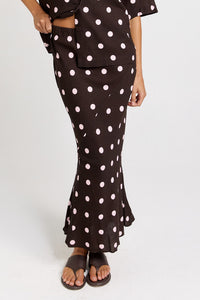 Front view of the Betty Basics Sable Bias Yoke Skirt in chocolate with pink polka dots, showing its long silhouette and flared hem.