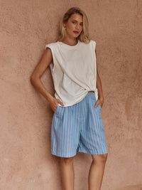 Model wearing the Sass Marley Knot Front Tank in white with blue striped shorts, showing its crew neckline and draped front hem.