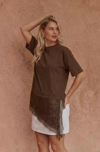 A model wearing the Sass Arlo Jersey Lace Tee in Chocolate with an asymmetrical satin lace hem, crew neckline and short sleeves