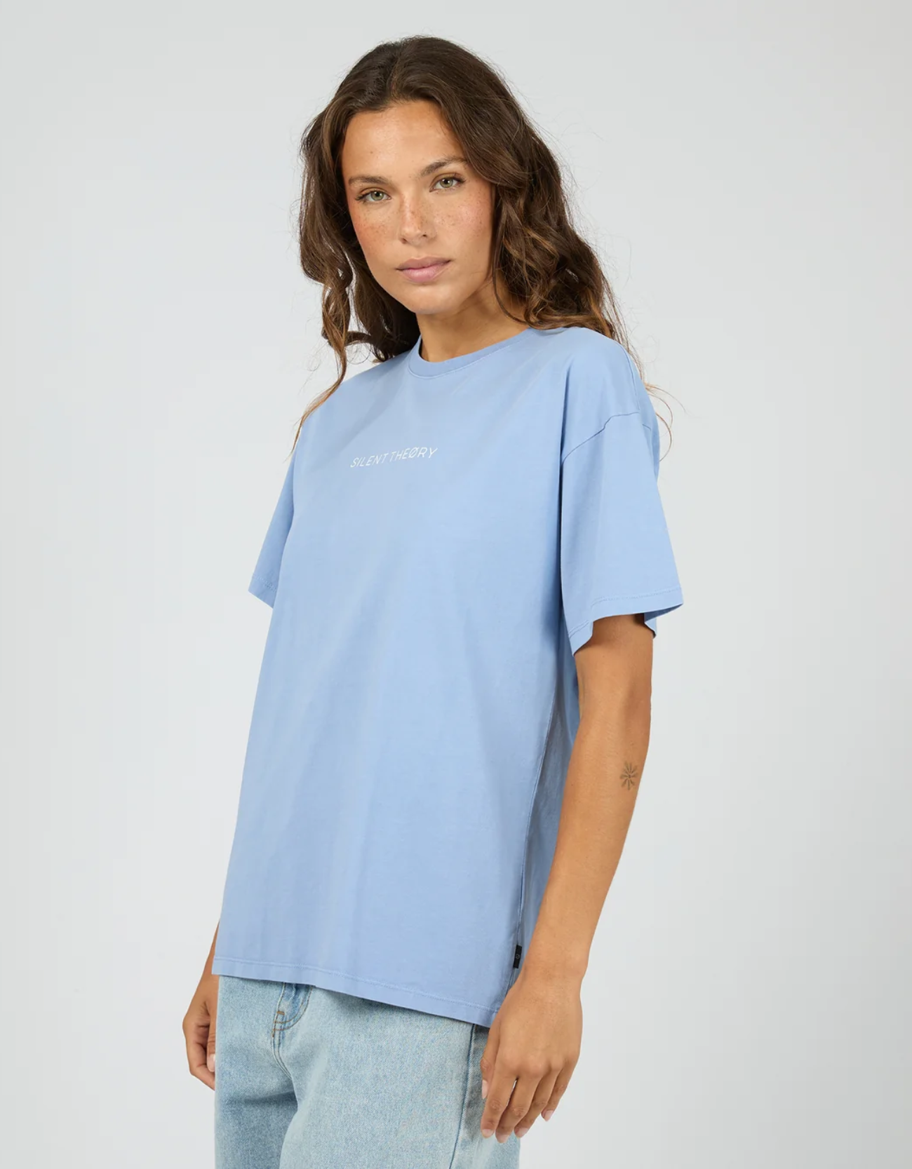 Silent Theory Logo Tee in Light Blue – three-quarter front angle highlighting Silent Theory chest logo print, crew neckline and boxy drop-shoulder fit in structured heavyweight light blue cotton