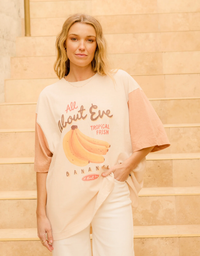All About Eve Tropical Oversized Tee in Vanilla, model by steps showing banana graphic and contrast sleeves.