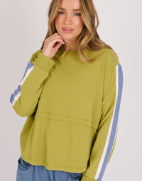 One Ten Willow Scoop Hem Long Sleeve Top in Olive with blue and white striped sleeves, styled with blue pants.
