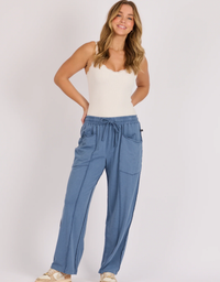 Model wearing the blue One Ten Willow relaxed pull-on pant with a cream camisole and beige sneakers.