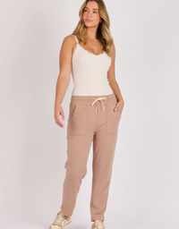 One Ten Willow Curve Hem Pant in Coffee, full front view on model with a white camisole and neutral sneakers.

