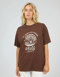 All About Eve Studios Relaxed Tee in Chocolate, front view on model showing cream shell graphic and Amalfi lettering.
