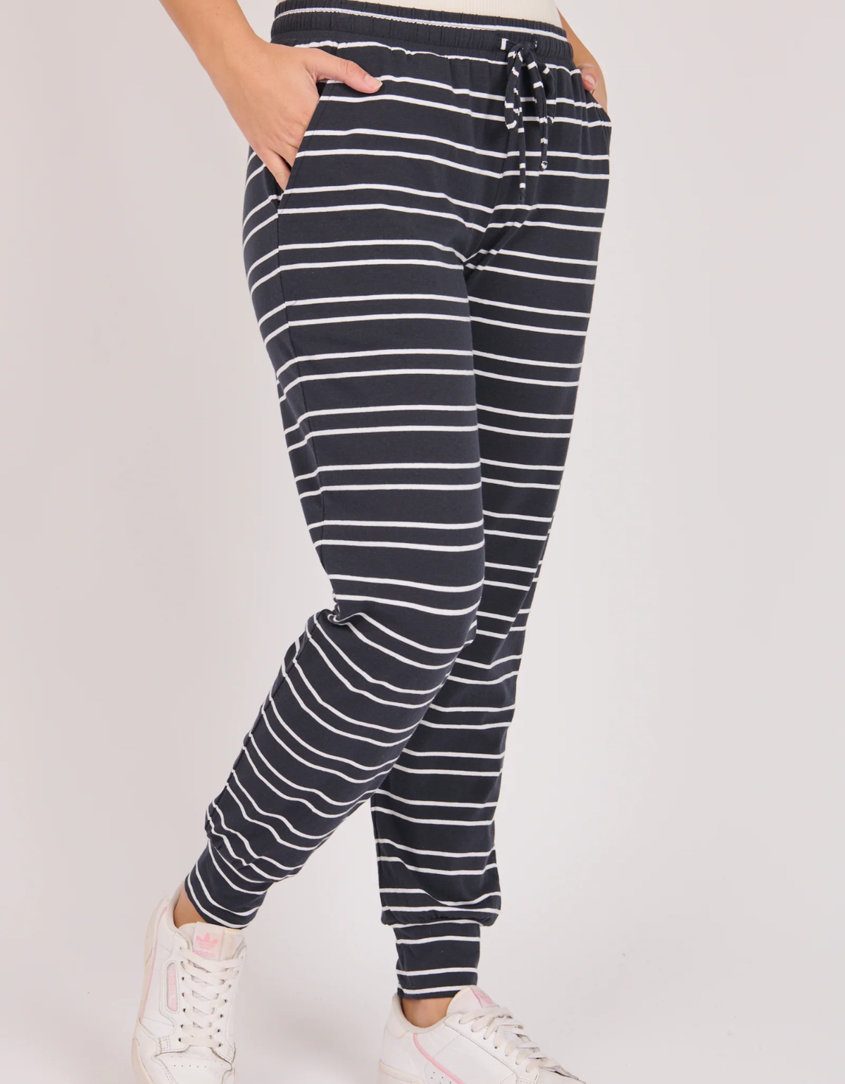 Model wearing the One Ten Willow Everyday Pant in Navy and white stripe showing a side view of a elasticated waist and relaxed silhouette

